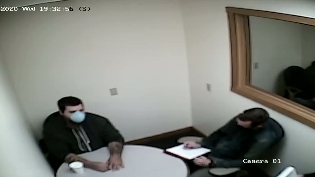 Surveillance-camera view of two men seated at a table during a recorded interrogation